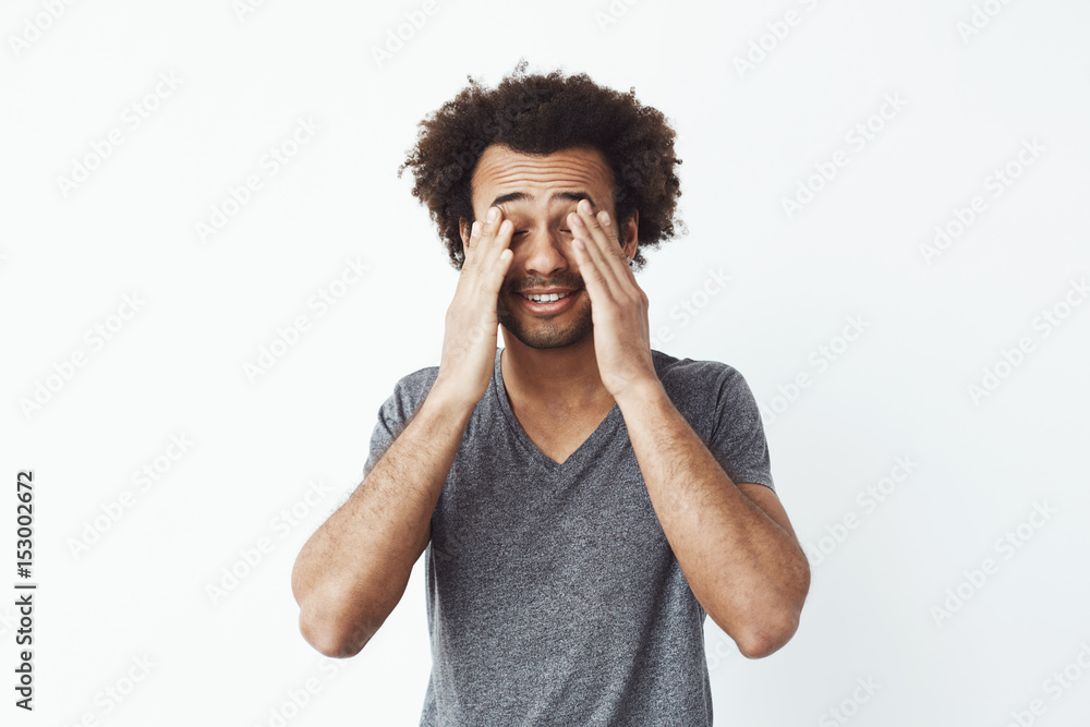 Bored tired african man touching face with hands over white background. Bored tired african man touching face with hands over white background.