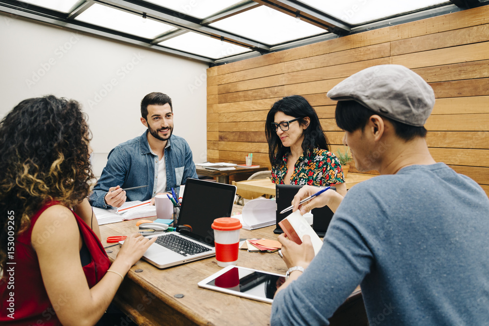 Startup of four multiethnic people discussing joyfully ideas in a modern coworking espace Startup of four multiethnic people discussing joyfully ideas in a modern coworking espace