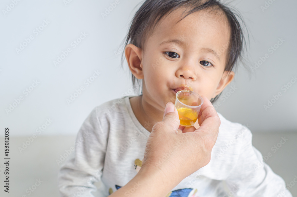 Asian little girl takes medicine syrup with her mother Asian little girl takes medicine syrup with her mother