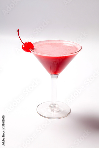 Red drink in martini glass, garnished with marachino cherry. on white background photo