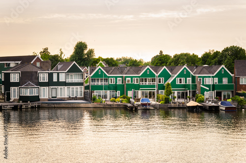 Traditional Wooden Houses along a Canal in the Netherlands at Sunset © alpegor