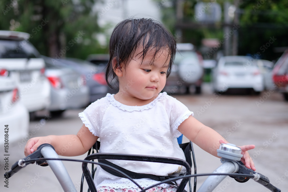 Obraz premium Cute Baby girl is sitting on a bicycle., close-up portrait, Portrait of Asian beautiful baby girl of 1 year and 3 months old.