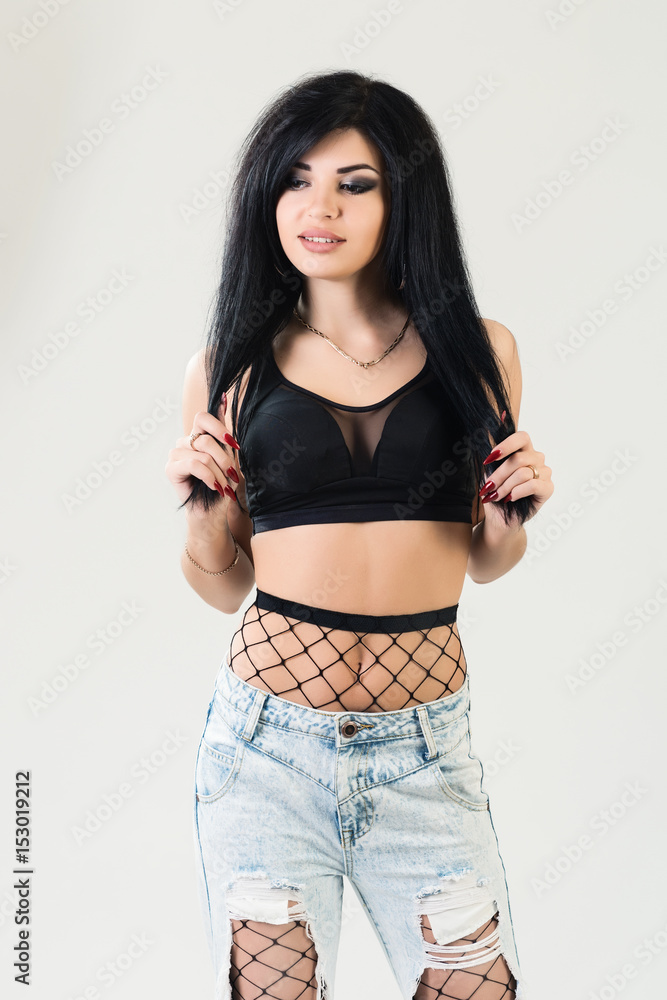 Close-up fashion portrait of young stylish hipster girl posing, stylish women's look, black top and trendy jeans with fishnet pantyhose Close-up fashion portrait of young stylish hipster girl posing, stylish women's look, black top and trendy jeans with fishnet pantyhose