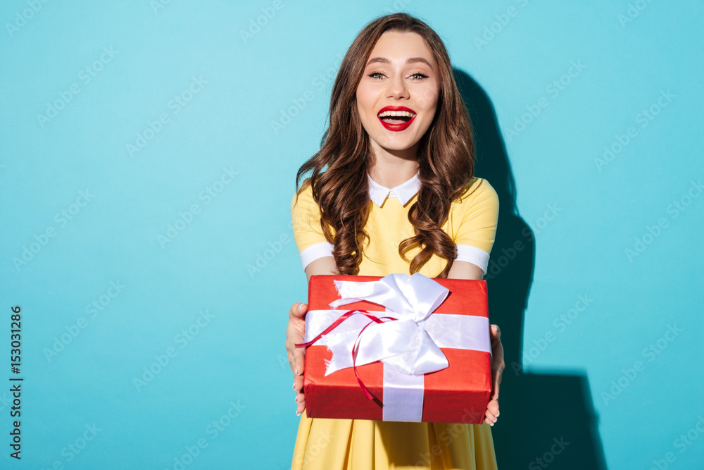 Cheerful pretty girl in dress giving present box to camera Cheerful pretty girl in dress giving present box to camera
