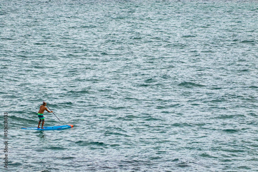 Man on paddle-board in a vast ocean Man on paddle-board in a vast ocean