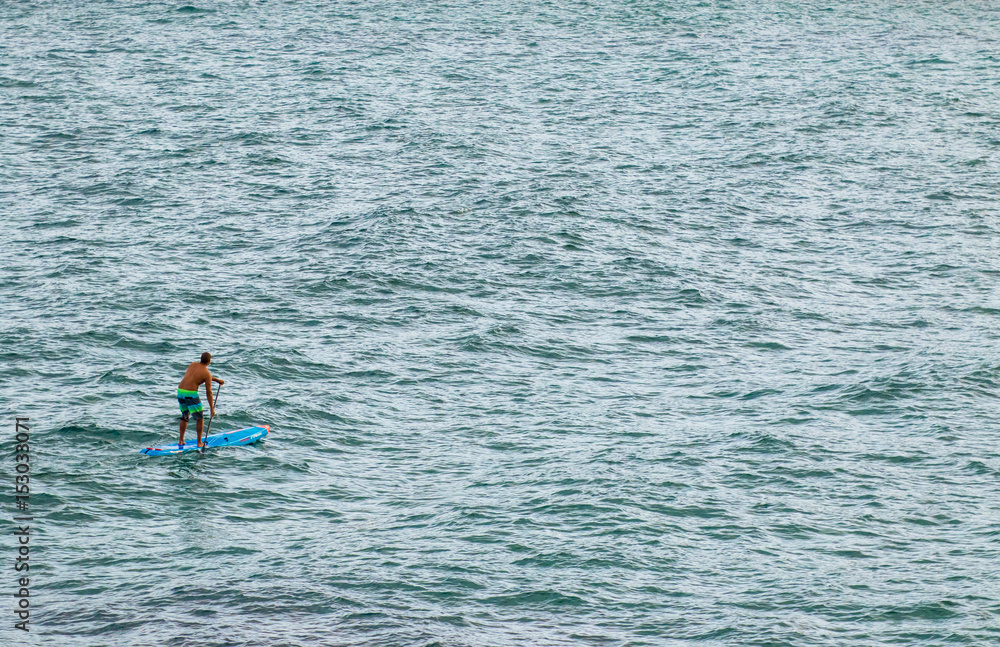 Man on paddle-board in a vast ocean