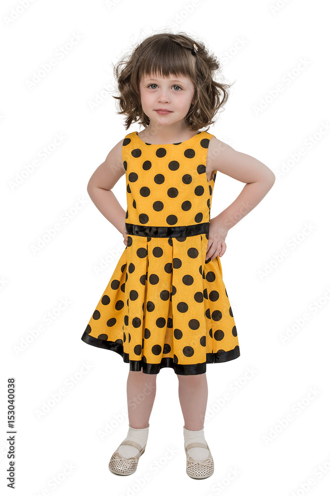 A little charming girl in a bright yellow dress, stares forward with an important air, hands on her hips A little charming girl in a bright yellow dress, stares forward with an important air, hands on her hips