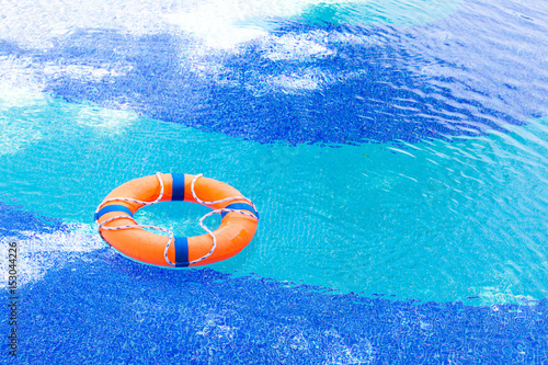 Orange lifebuoy float in pool with copy space