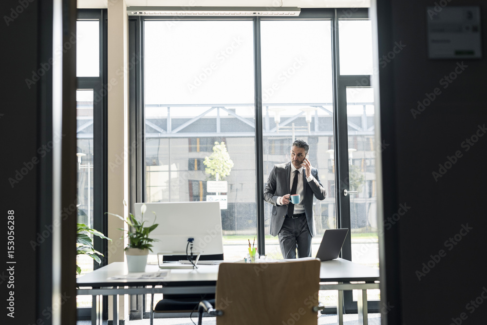 Businessman with cup of coffee on the phone in his office Businessman with cup of coffee on the phone in his office