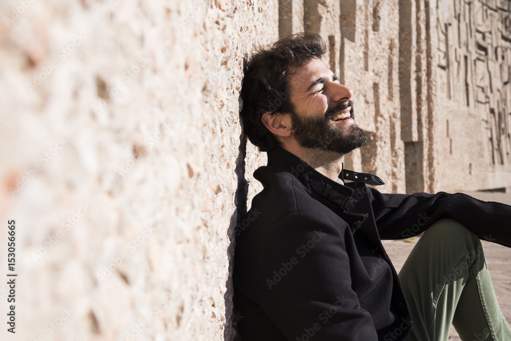 Laughing man with eyes closed leaning against wall Laughing man with eyes closed leaning against wall