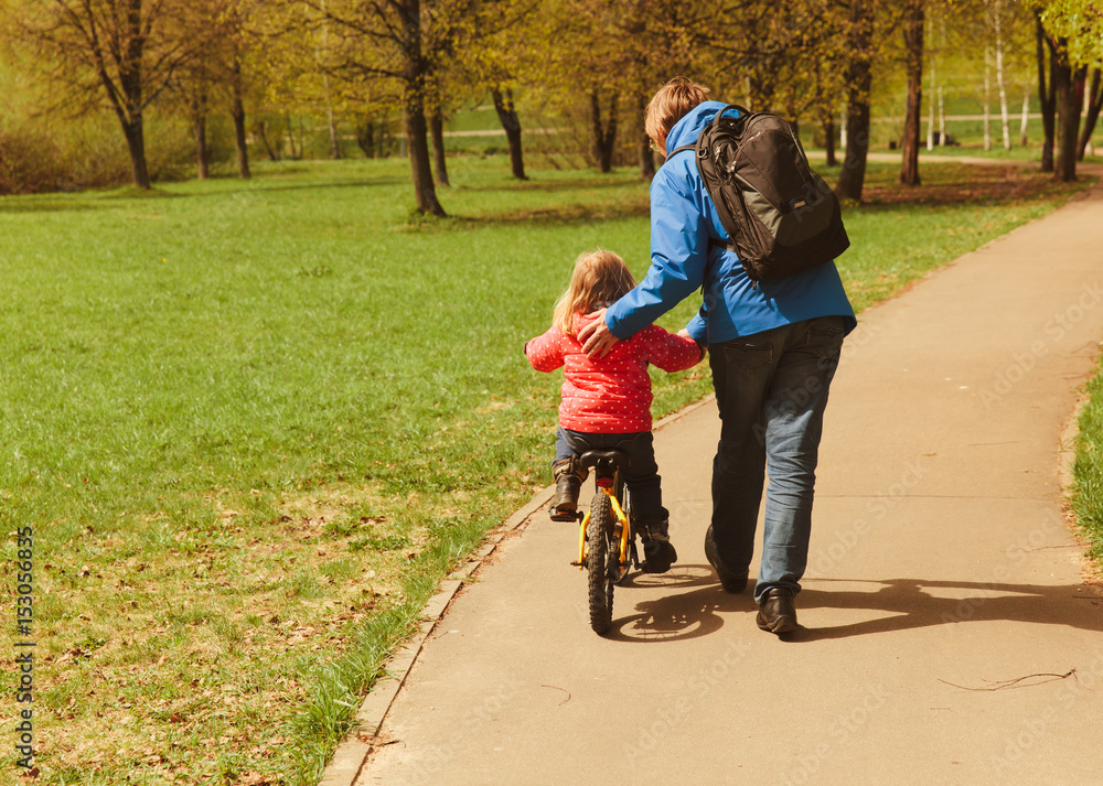 Fototapeta premium father teaching little daughter to ride bicycle