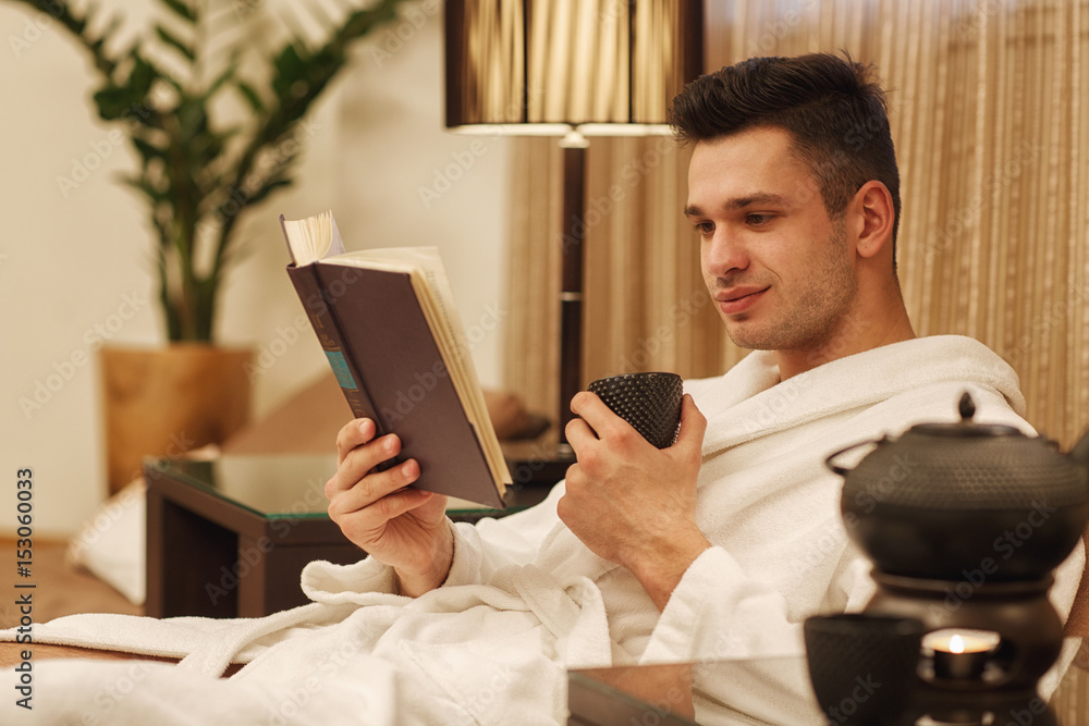 Handsome man having tea reading a book Handsome man having tea reading a book