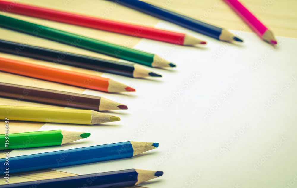 Fototapeta premium Row of colorful pencils on a wooden table/colored pencils and the sheet of paper