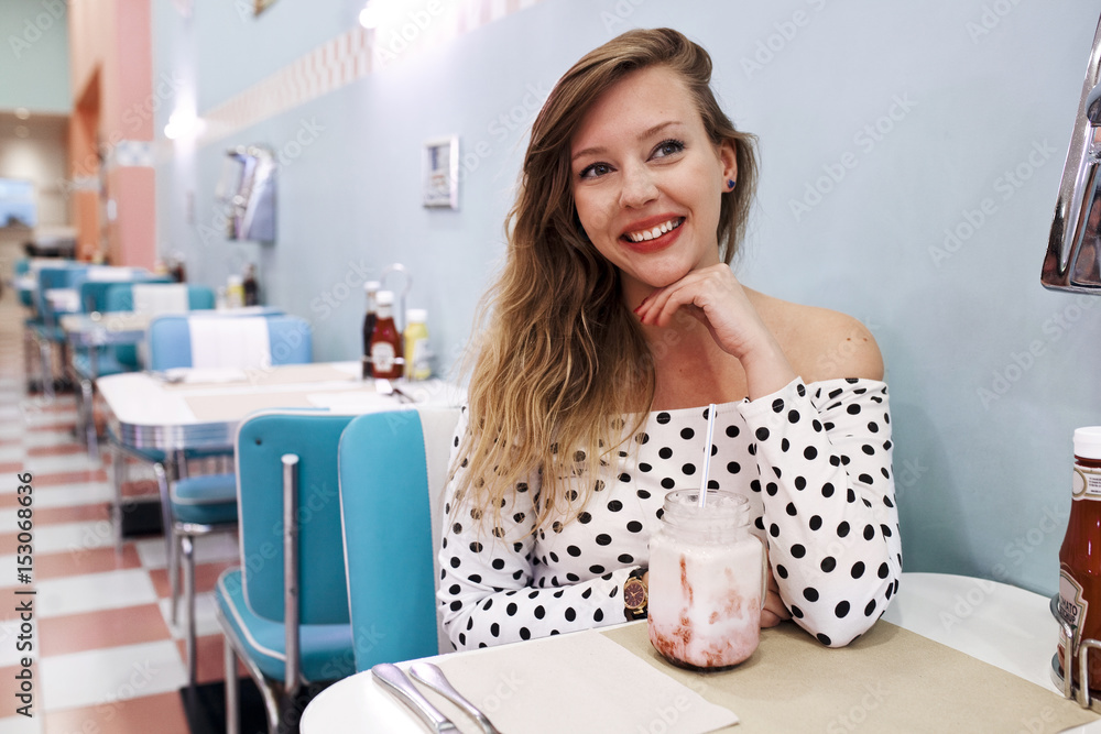 Smiling young woman drinking milkshake in restaurant Stock Photo ...