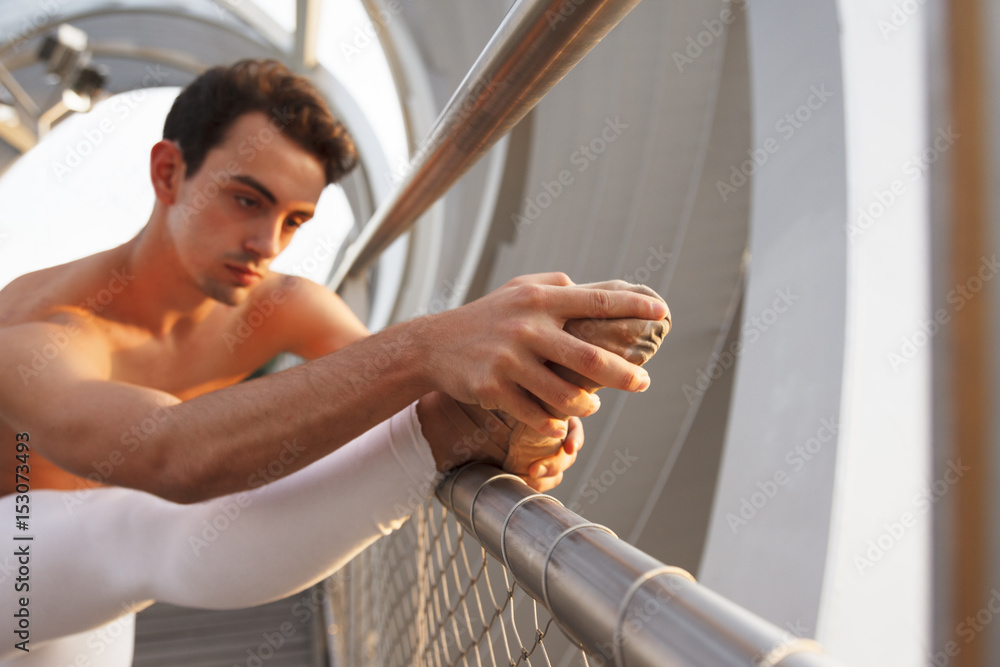 Fototapeta premium young male ballet dancer stretching and touching the tip of his ballerina shoe