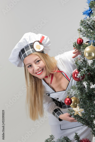 Young and beaituful chef looking behing christmas tree photo