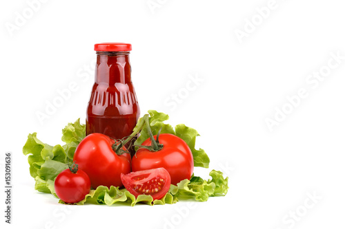 Red ripe tomatoes and a bottle of tomato sauce on a white background.