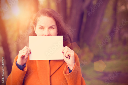 Young woman holding blank shhet of paper near face photo