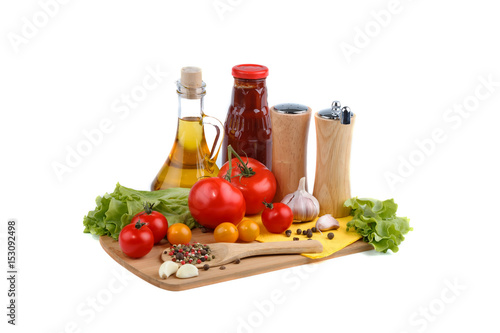 Still life of red and yellow tomatoes, bottle of tomato sauce and olive oil on white background.