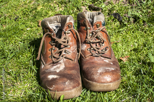 Old used weathered moldy grunge man s leather shoes on green grass field