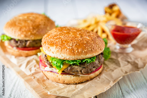 American hamburger with beef, sauce and french fries on wood background. Flat lay. Top view.