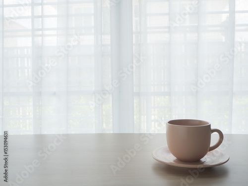 wood table with coffee cup on beautiful white drape window texture background.