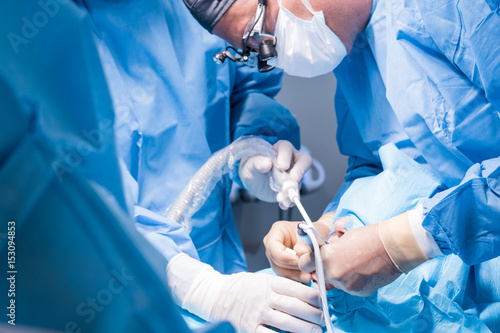 A male dentist in uniform perform dental implantation operation on a patient at dentistry office.