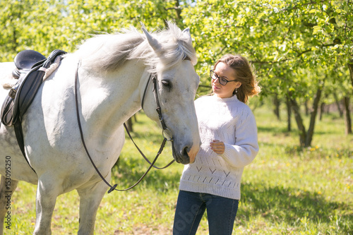 Beautiful girl is driving a white horse