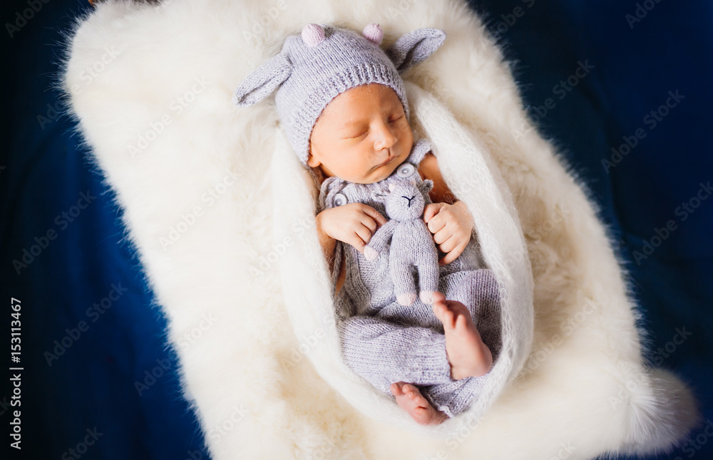 Child in knitted suit dreams on white pillow Child in knitted suit dreams on white pillow