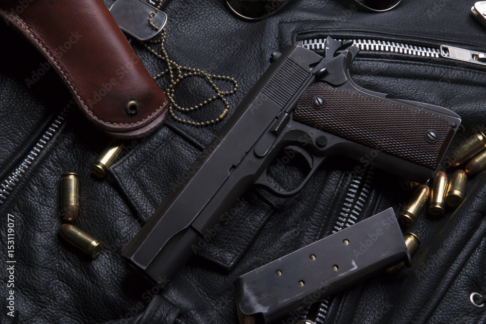 Gun Colt with bullets and holster rests on a leather jacket Gun Colt with bullets and holster rests on a leather jacket