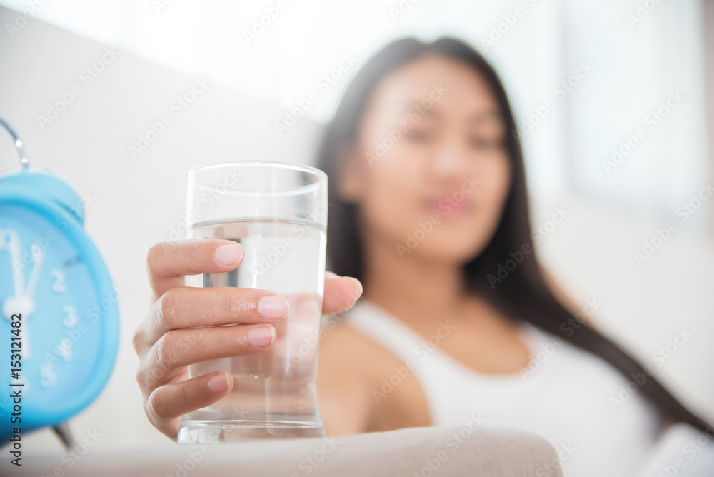 Close up Asian Woman holding glass of water with alarm clock. Close up Asian Woman holding glass of water with alarm clock.