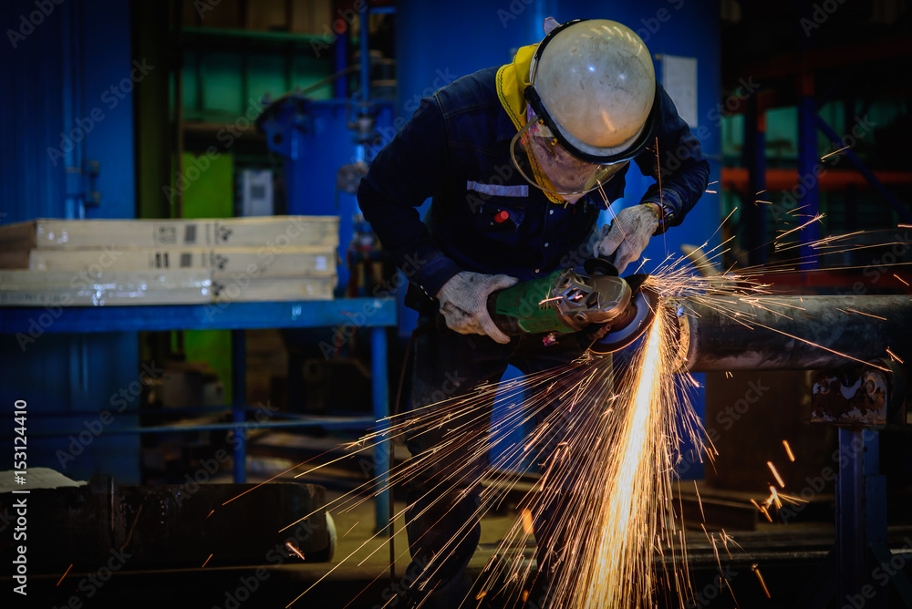 Heavy industrial worker used electric wheel grinding on steel structure in steel factory with sparks. Heavy industrial worker used electric wheel grinding on steel structure in steel factory with sparks.