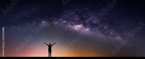 Landscape with Milky way galaxy. Night sky with stars and silhouette happy man on the mountain. Long exposure photograph.