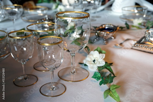 Antique gold rimmed drinking glasses on an ornate dining table