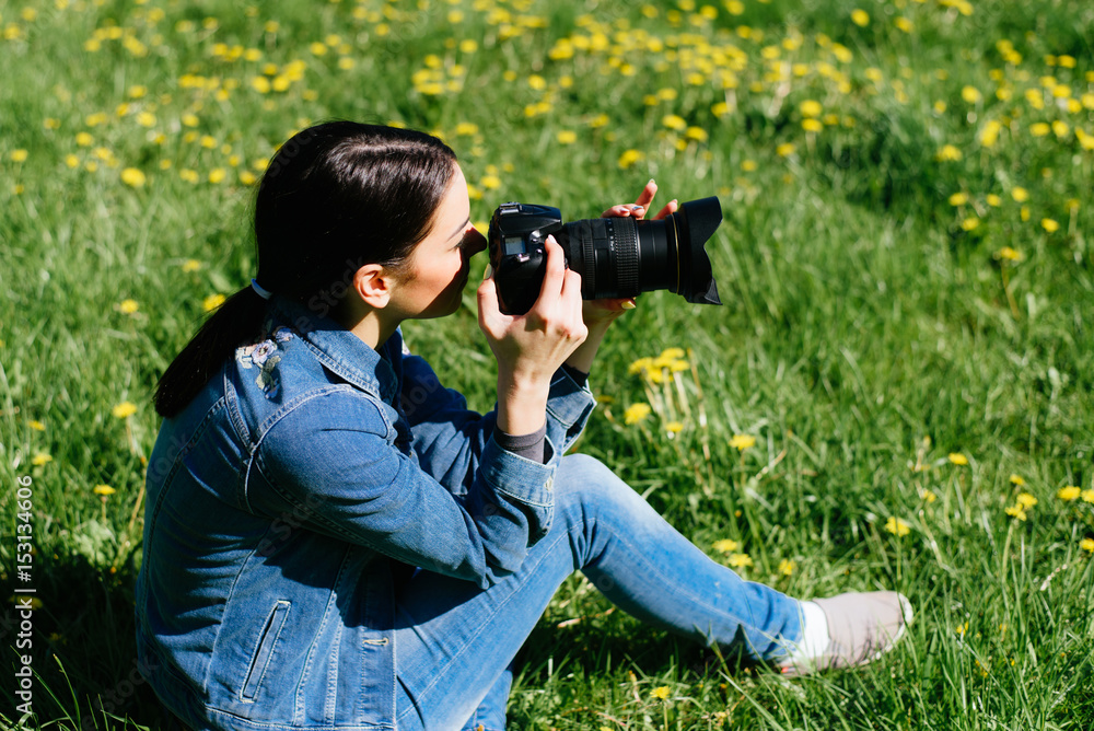 Attractive girl in a meadow takes pictures of flowers Attractive girl in a meadow takes pictures of flowers