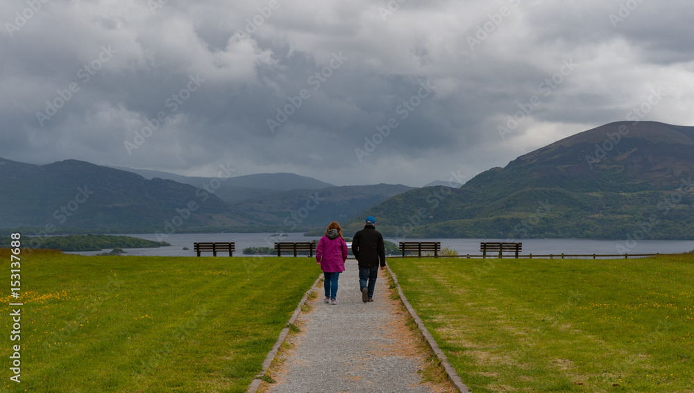 Couple walking on a path towards a viewing point of the lakes and mountains of Killarney national park