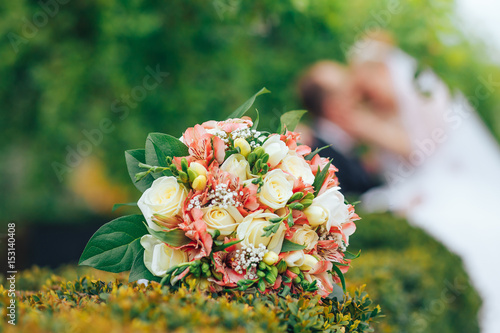 wedding bouquet on green grass in the background sit the couple