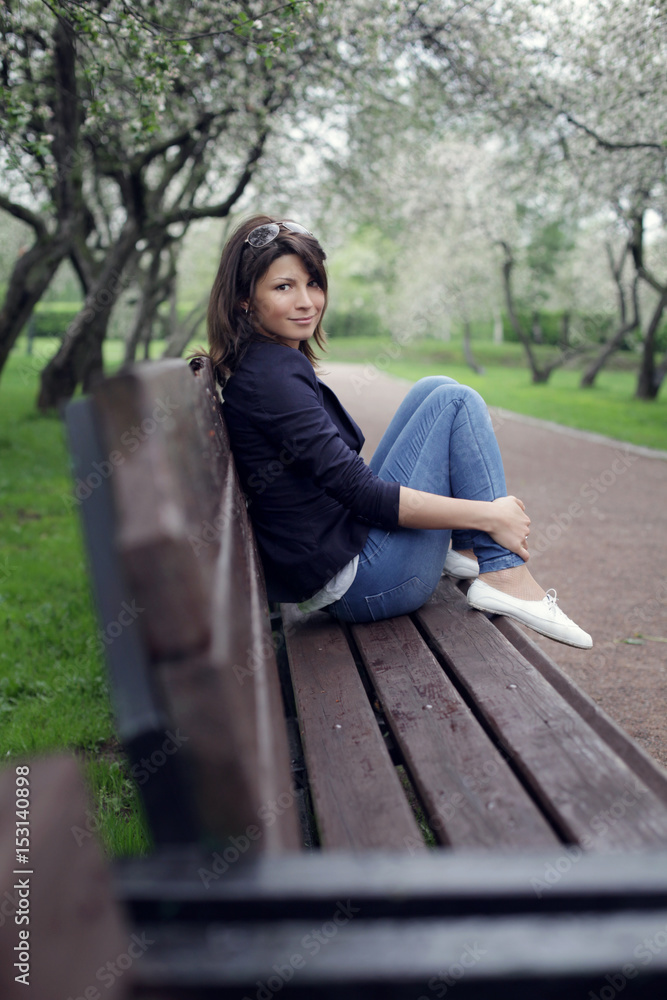 Smiling girl sits on a park bench 
