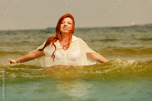 Redhead woman playing in water during summertime