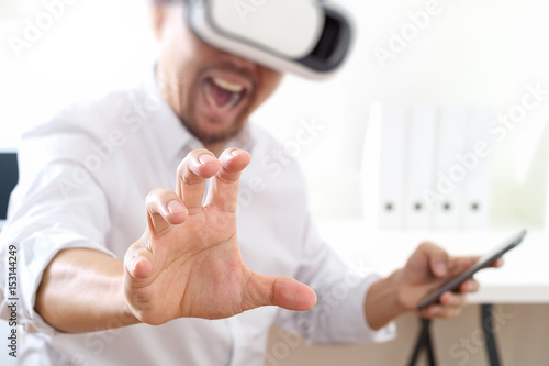 businessman wearing virtual reality goggles in modern office with mobile phone using with VR headset