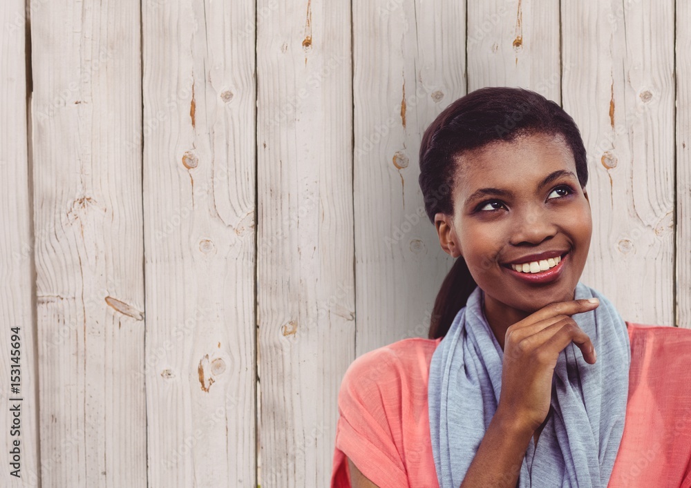 Thoughtful female hipster smiling against wooden Thoughtful female hipster smiling against wooden