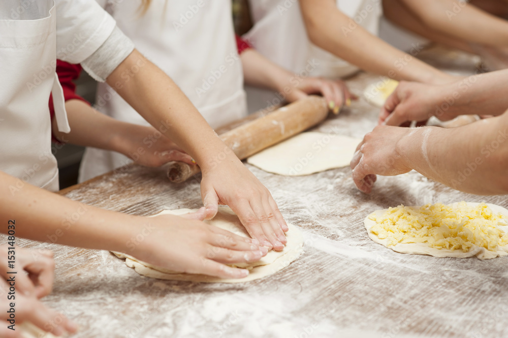 Making pastries from dough with stuffing. Children's hands close-up.