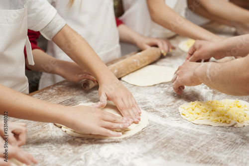 Making pastries from dough with stuffing. Children's hands close-up. © Rakursstudio