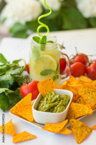 Homemade lemonade with salsa guacamole with corn chips and vegetables