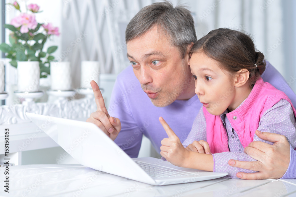 Father with a little daughter using a laptop