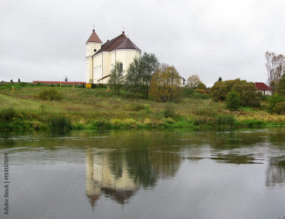 Old church on a hill, reflection in a river 