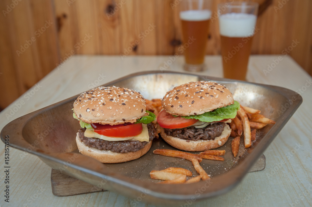 Hamburger with beef, cheese, onion, tomato, sauce, french fries and beer. Homemade burger. Hamburger with beef, cheese, onion, tomato, sauce, french fries and beer. Homemade burger.