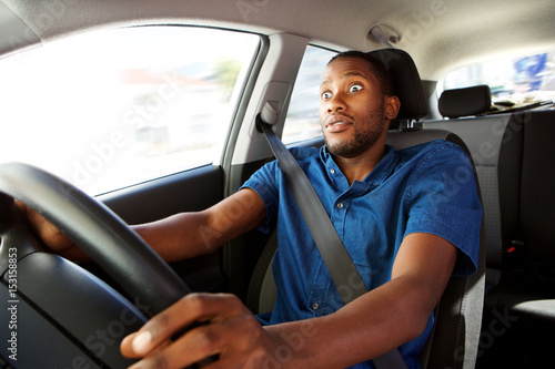 Young man driving a car with surprised expression