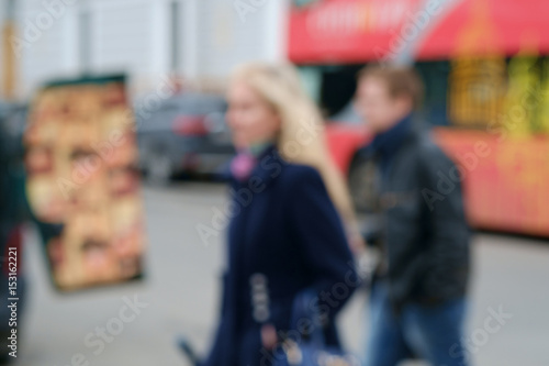 Blurred background with a young blond women and a man with red London double decker