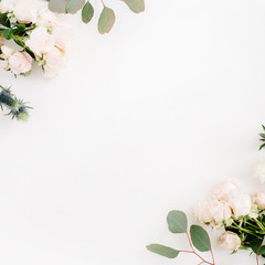 Border frame made of beige rose flowers, eringium flower, eucalyptus branches on white background. Flat lay, top view. Floral background